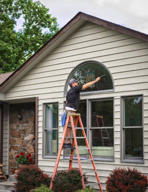 Guy cleaning window he has a ladder and its orange to get to the top