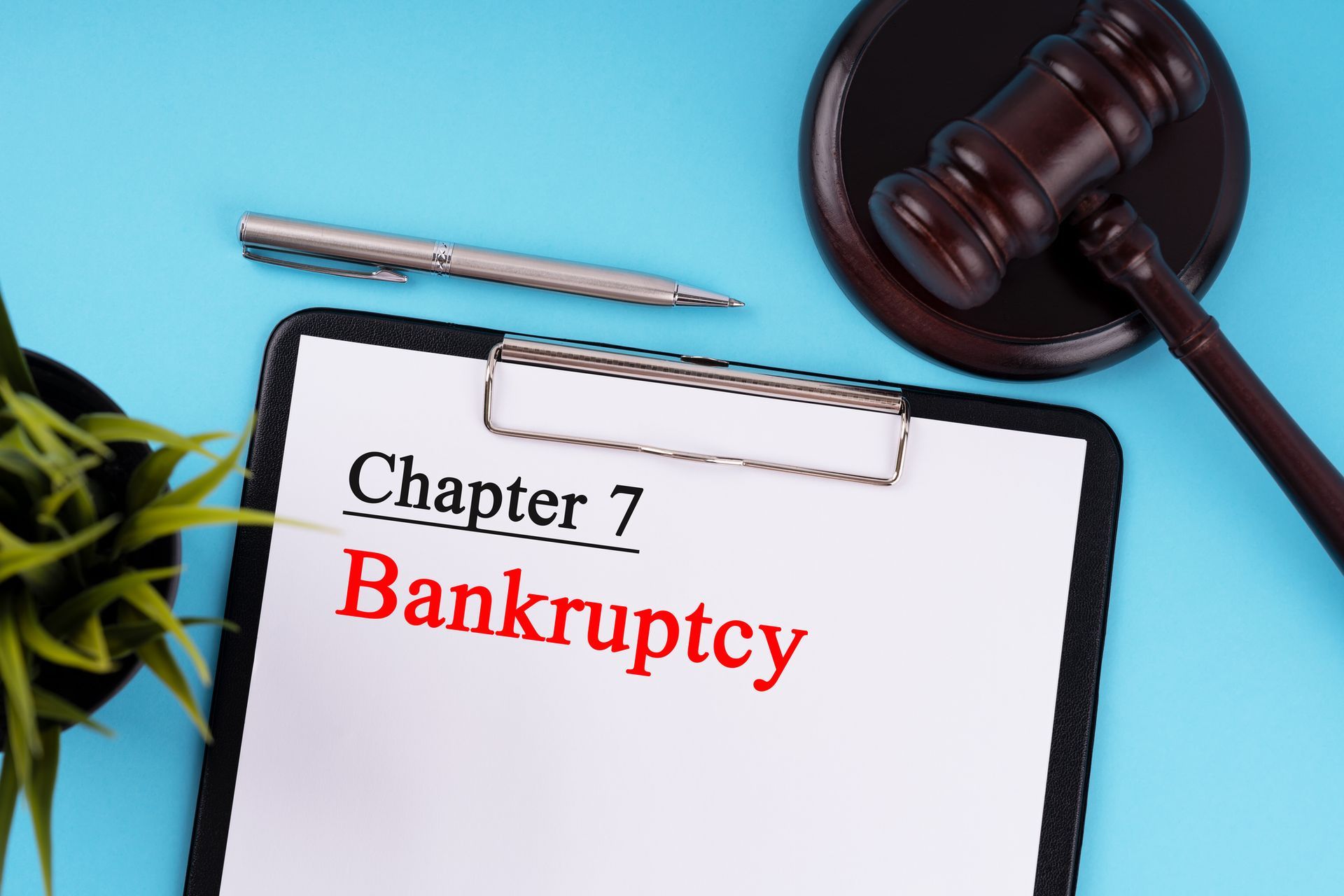 Chapter 7 Bankruptcy lawyer concept with clipboard, legal paperwork, gavel, pen, and plant on desk.