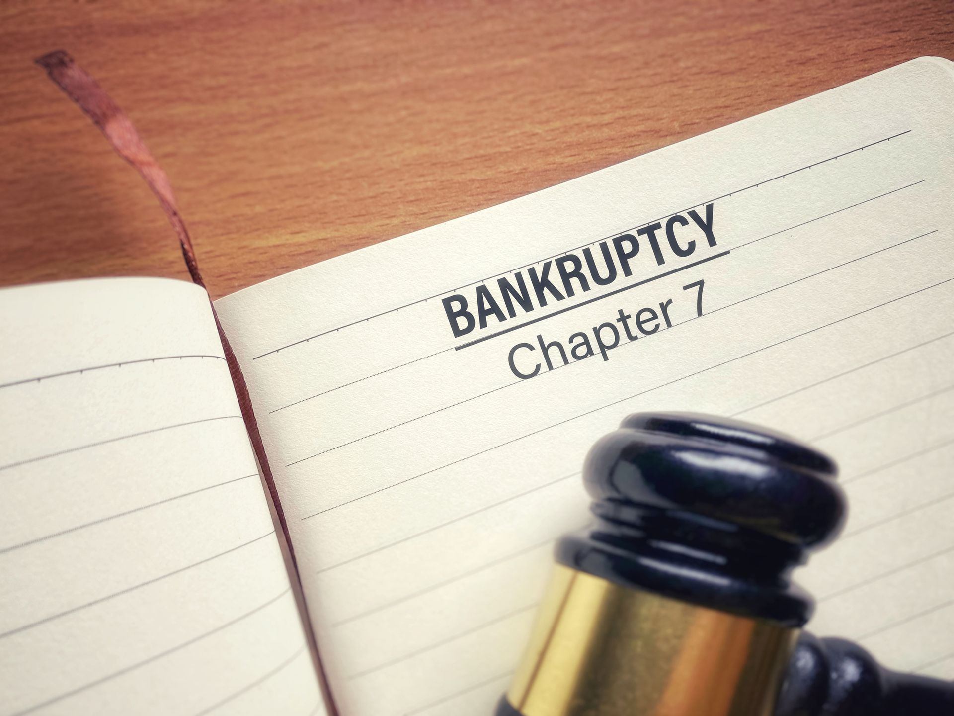 Chapter 7 bankruptcy lawyer concept showing gavel and notebook on wooden desk for legal case. Chapter 7 bankruptcy lawyer concept showing gavel and notebook on wooden desk for legal case.