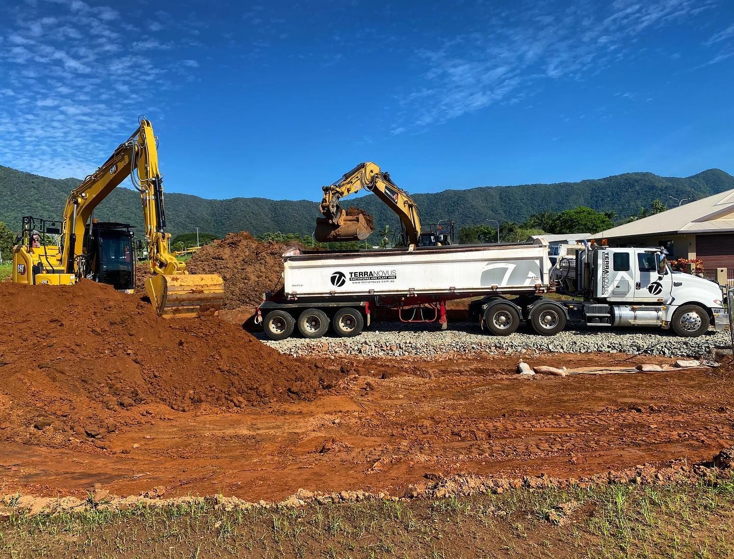 Two Excavators Loading a Dump Truck With Dirt on a Construction Site — Terranovus Earthworks & Plant Hire in Cairns City, QLD