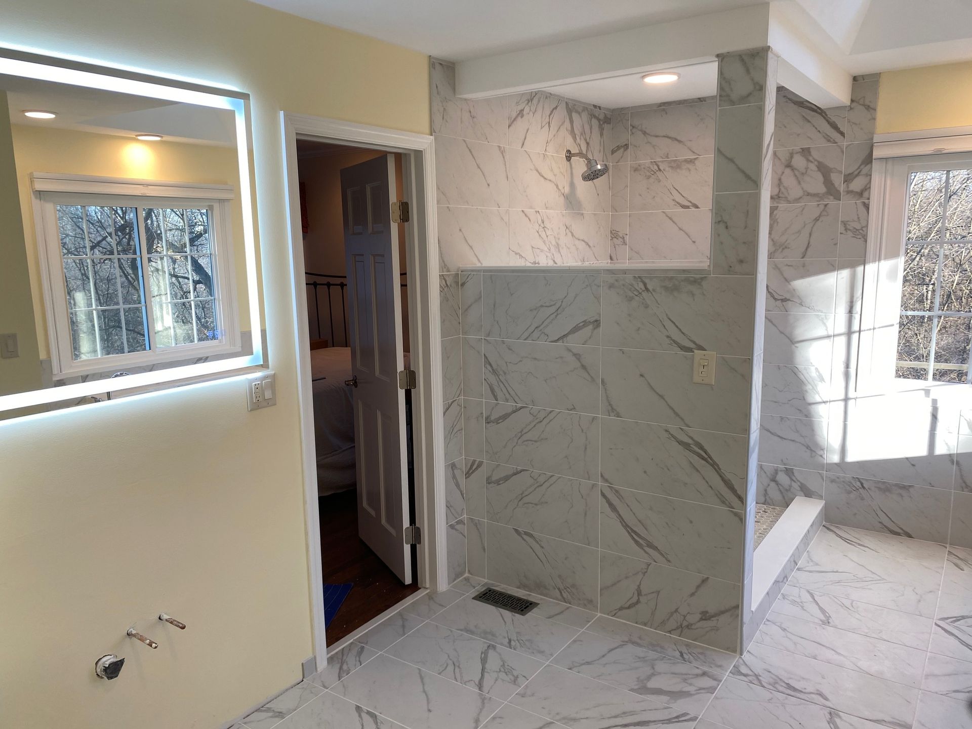 A bathroom with a walk in shower and a large mirror.