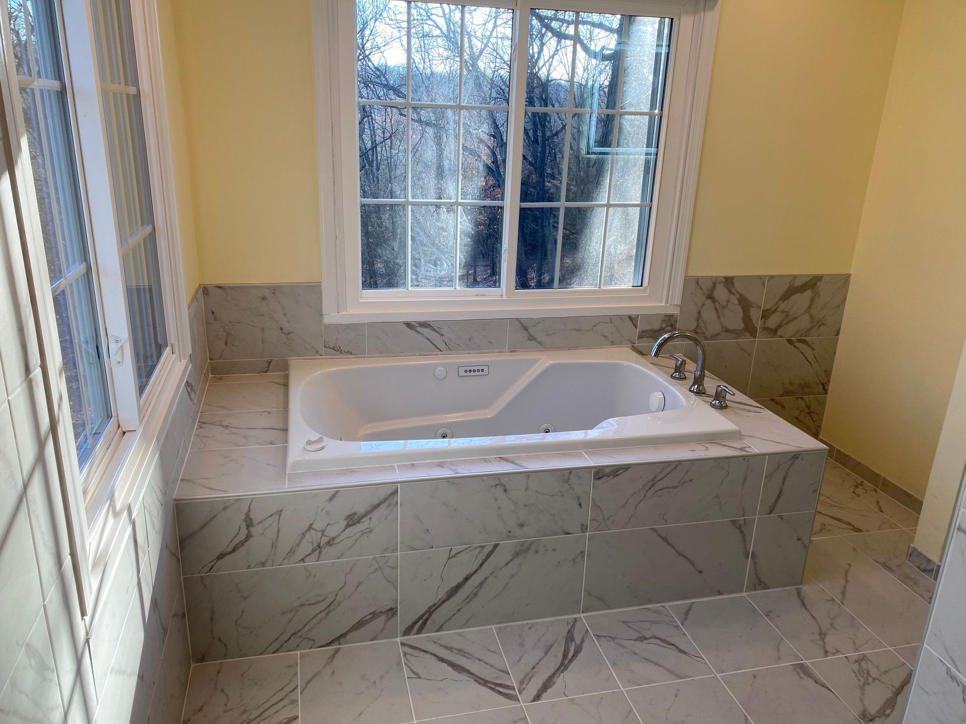 A bathroom with a jacuzzi tub and a window.