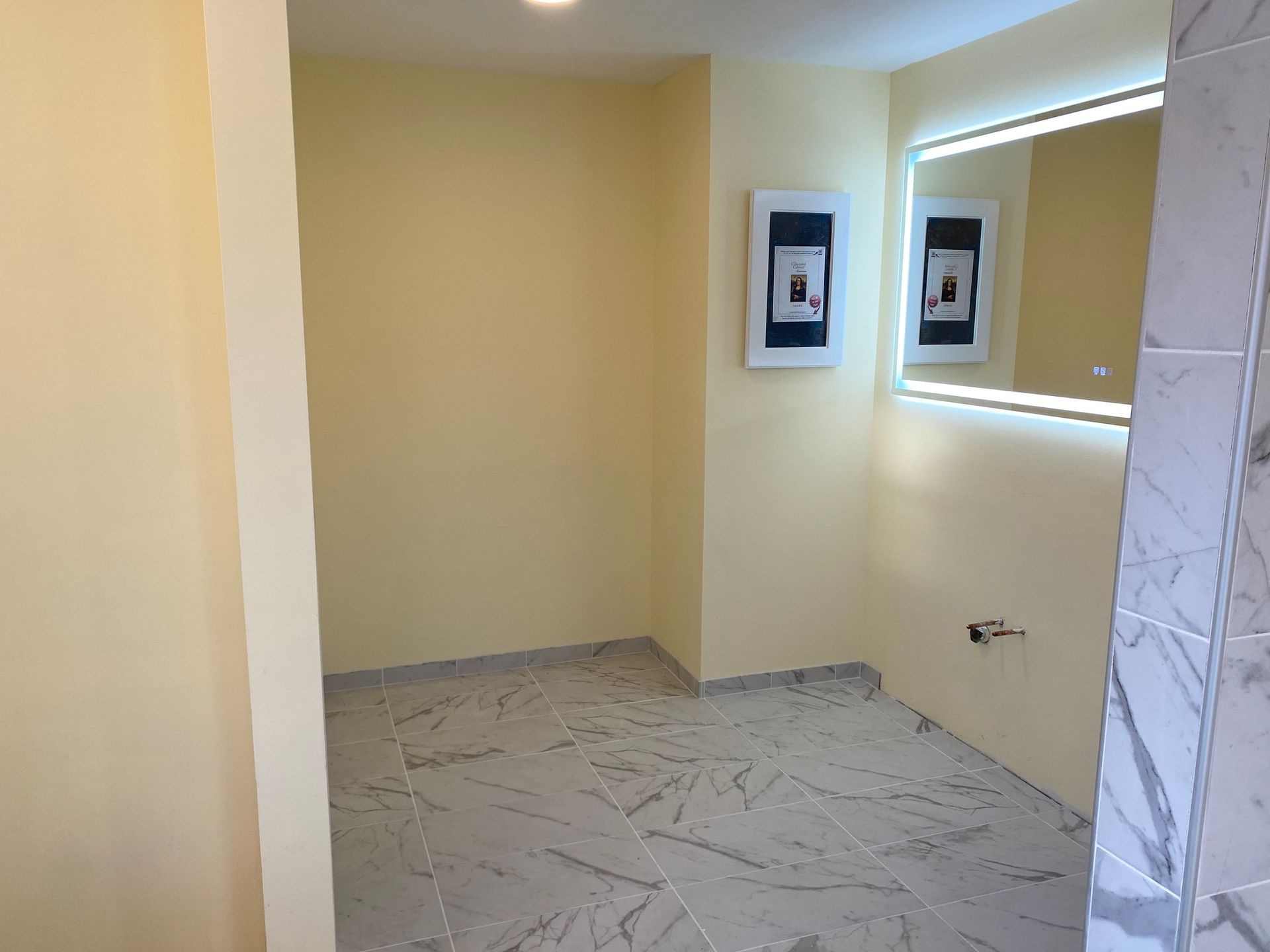 A bathroom with a large mirror and two pictures on the wall.