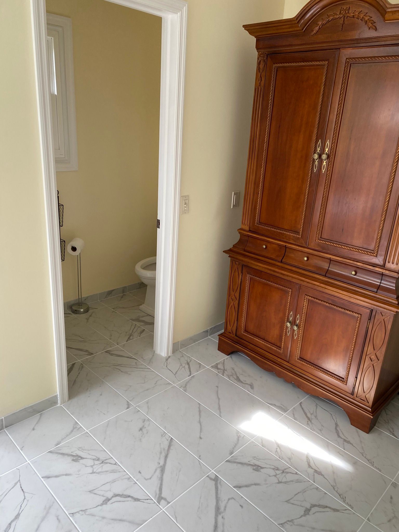 A bathroom with a wooden cabinet and a toilet.