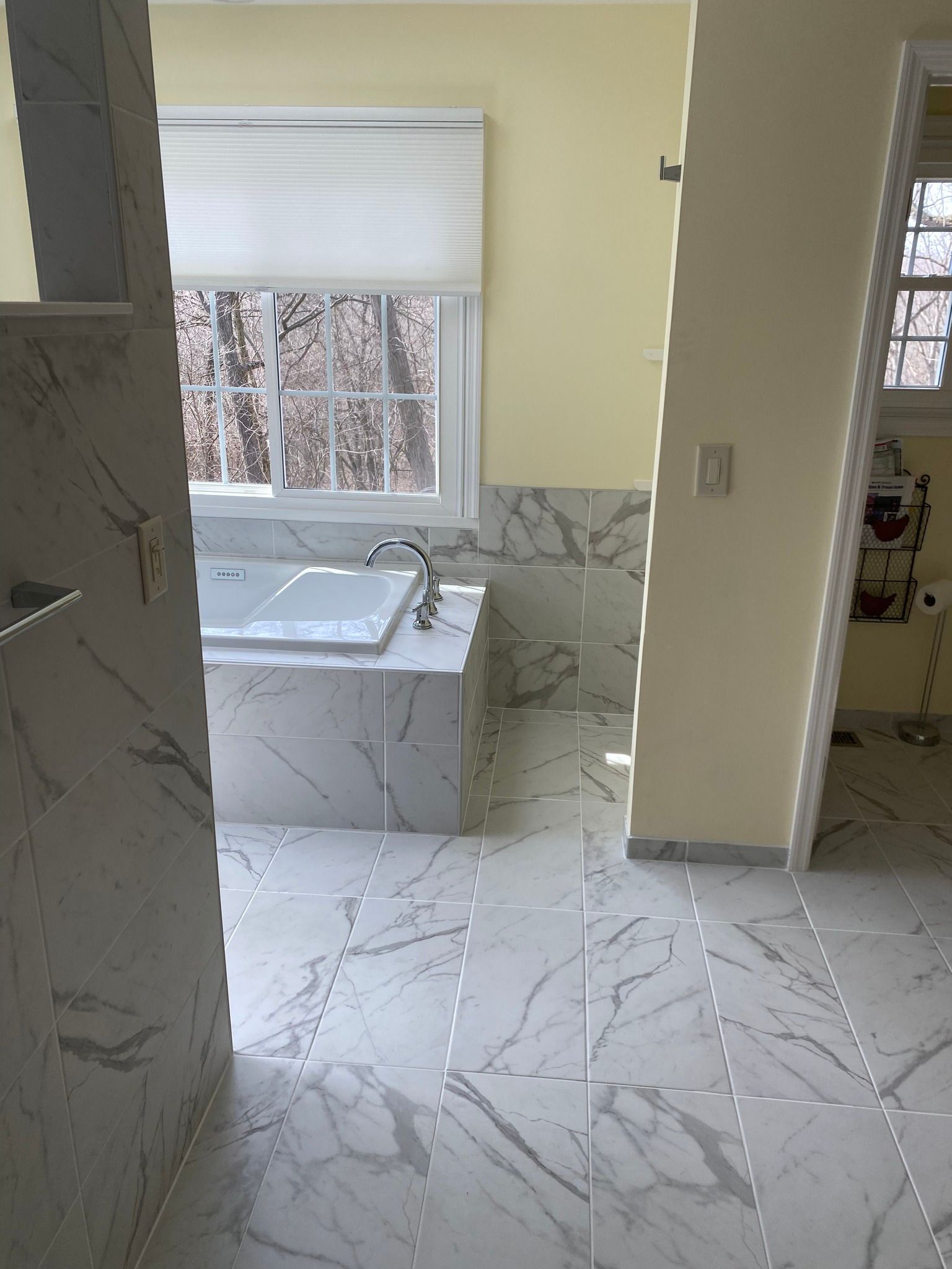 A bathroom with marble floors , a tub and a window.