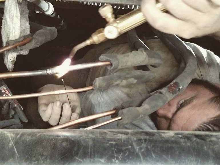 a man is welding copper pipes with a torch