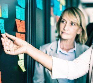 Professionals viewing a post-it note facilitation wall. Workshops and facilitations to train mentors, develop mentor schemes, career coaching for doctors.