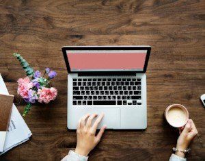 Woman typing of laptop and coffee. Blog on Career breaks, support, mentoring and coaching in medicine and career coaching.