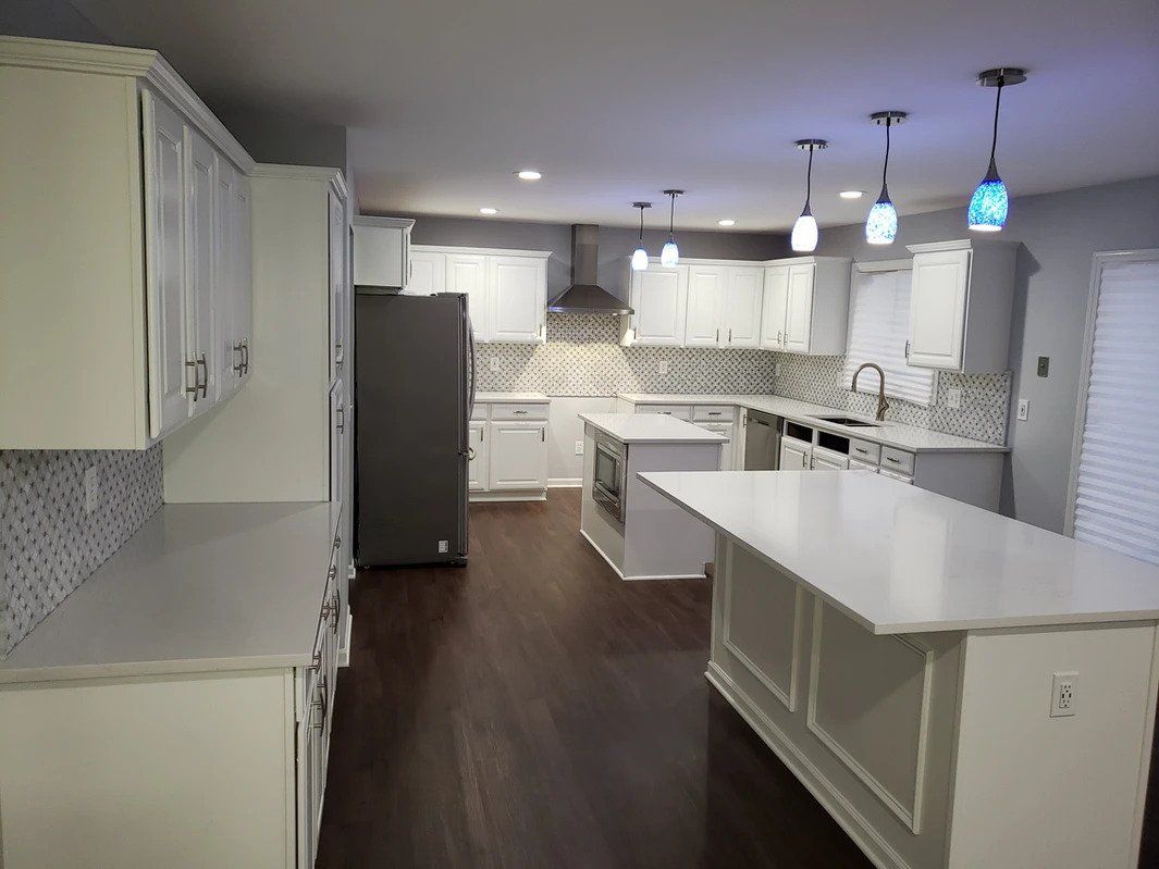 A kitchen with white cabinets and a large island in the middle