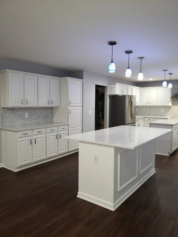 A kitchen with white cabinets and a large island in the middle.