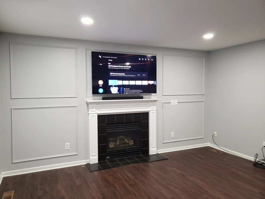 A living room with a fireplace and a flat screen tv on the wall.