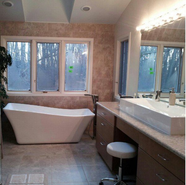 A bathroom with a tub a sink and a mirror