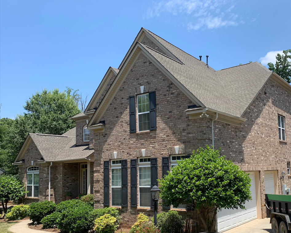 A large brick house with black shutters and a truck parked in front of it.