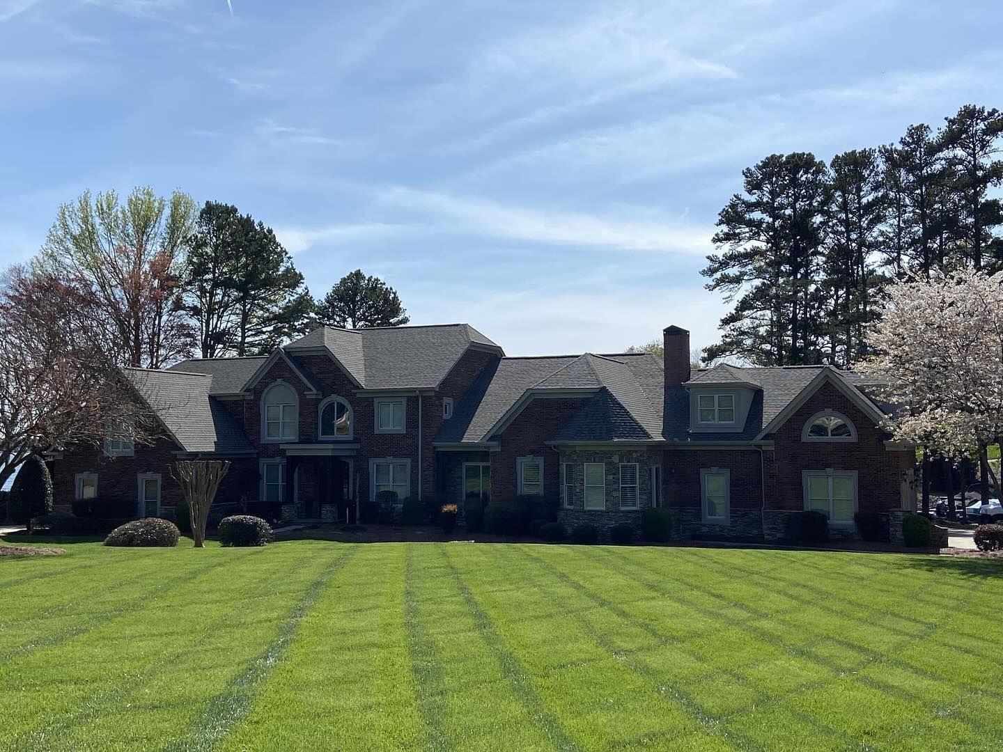 A large brick house with a lush green lawn in front of it