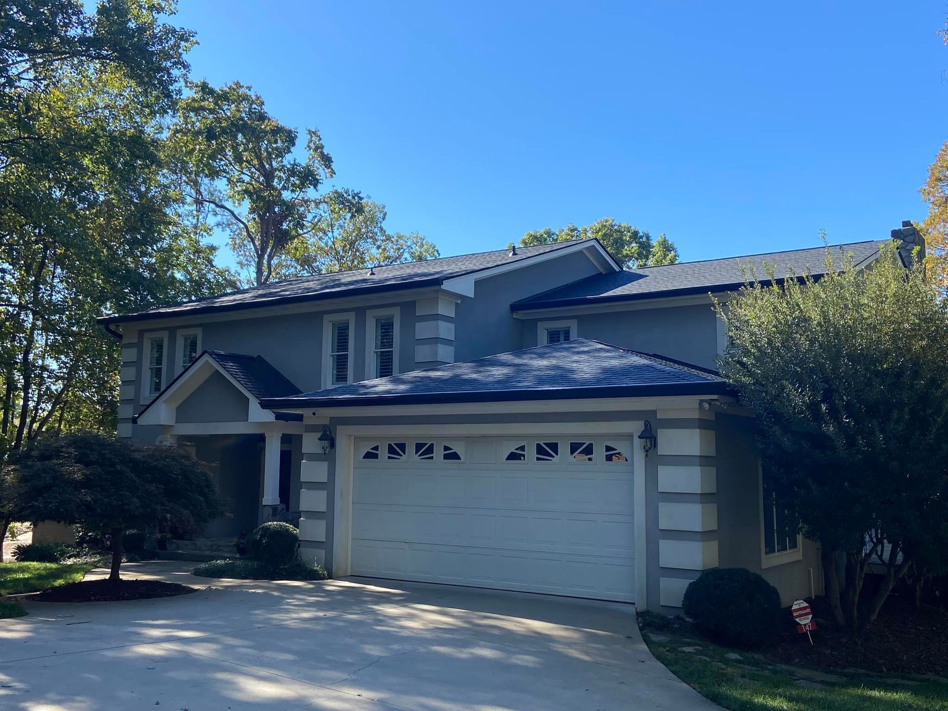 A large house with a white garage door and a blue sky in the background