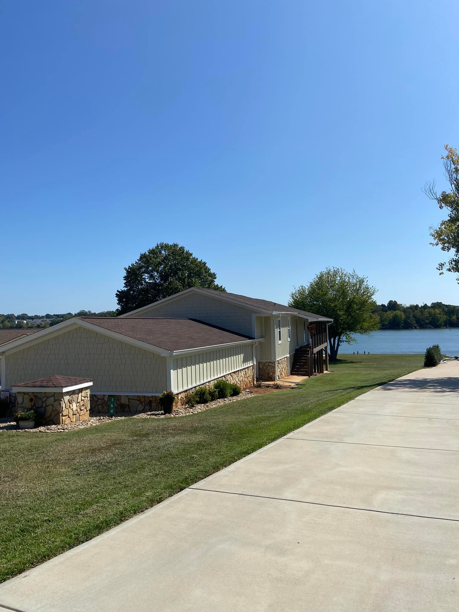 A driveway leading to a house with a lake in the background.