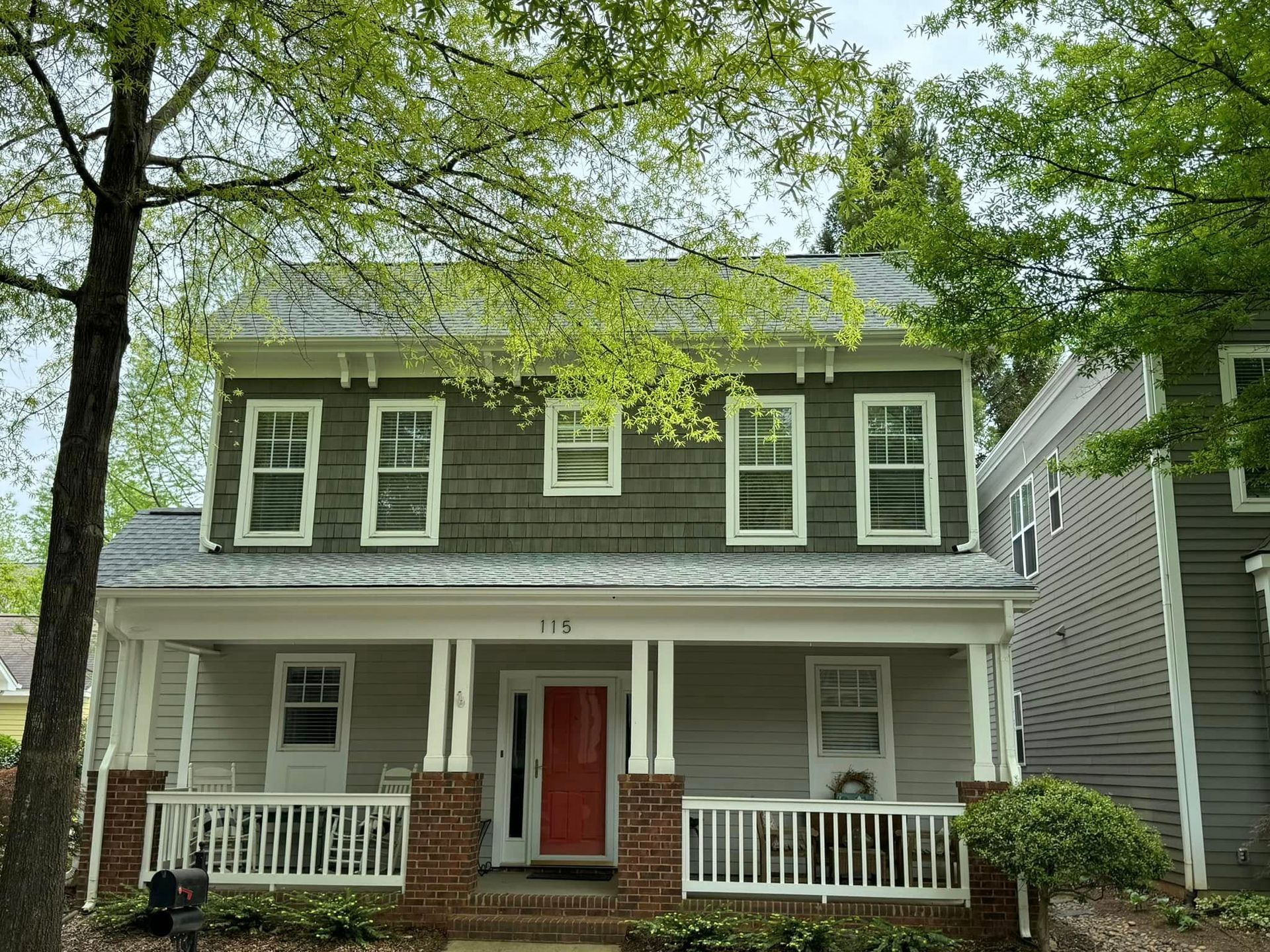 A house with a large porch and a red door