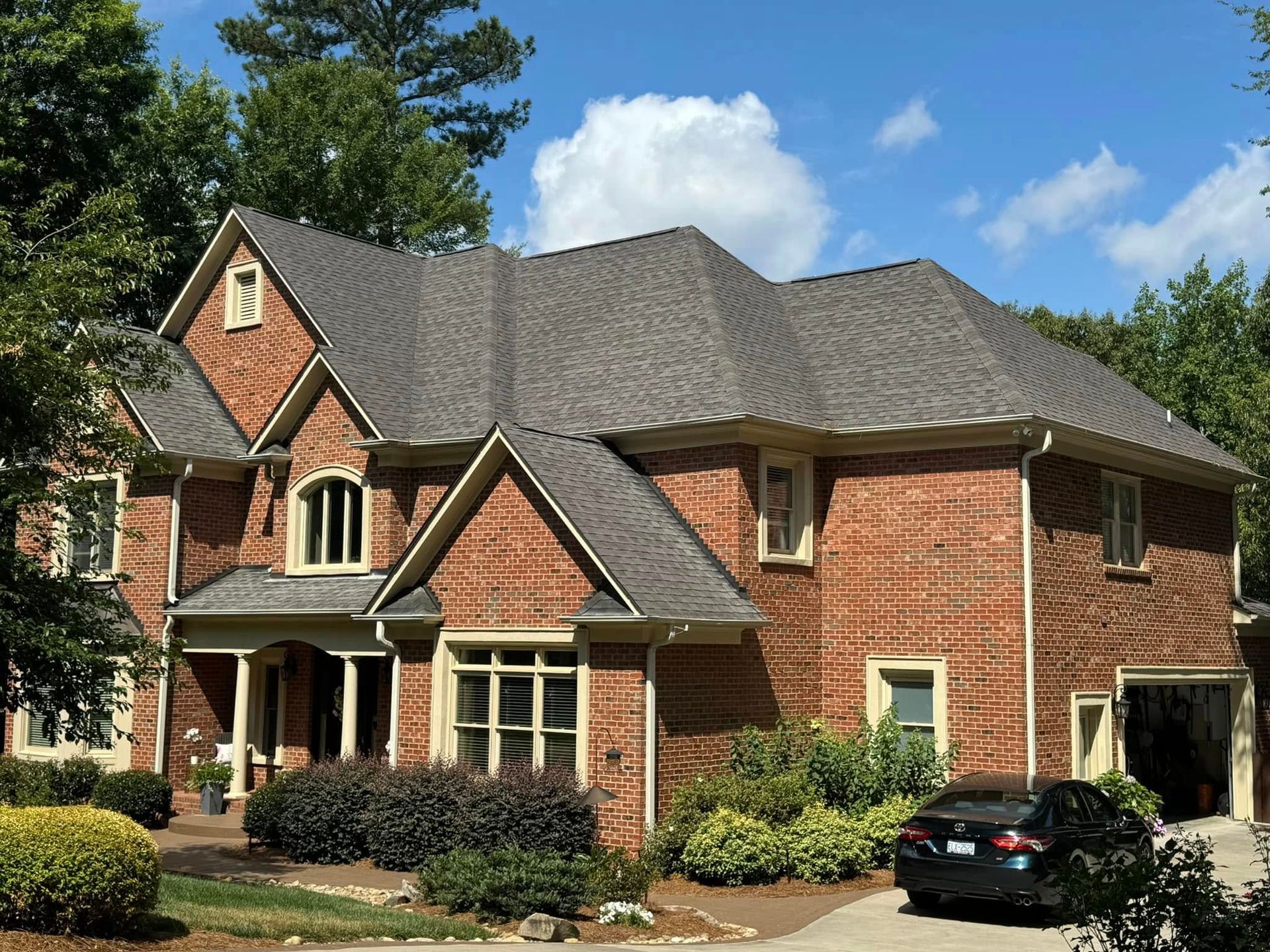 A large brick house with a car parked in front of it.