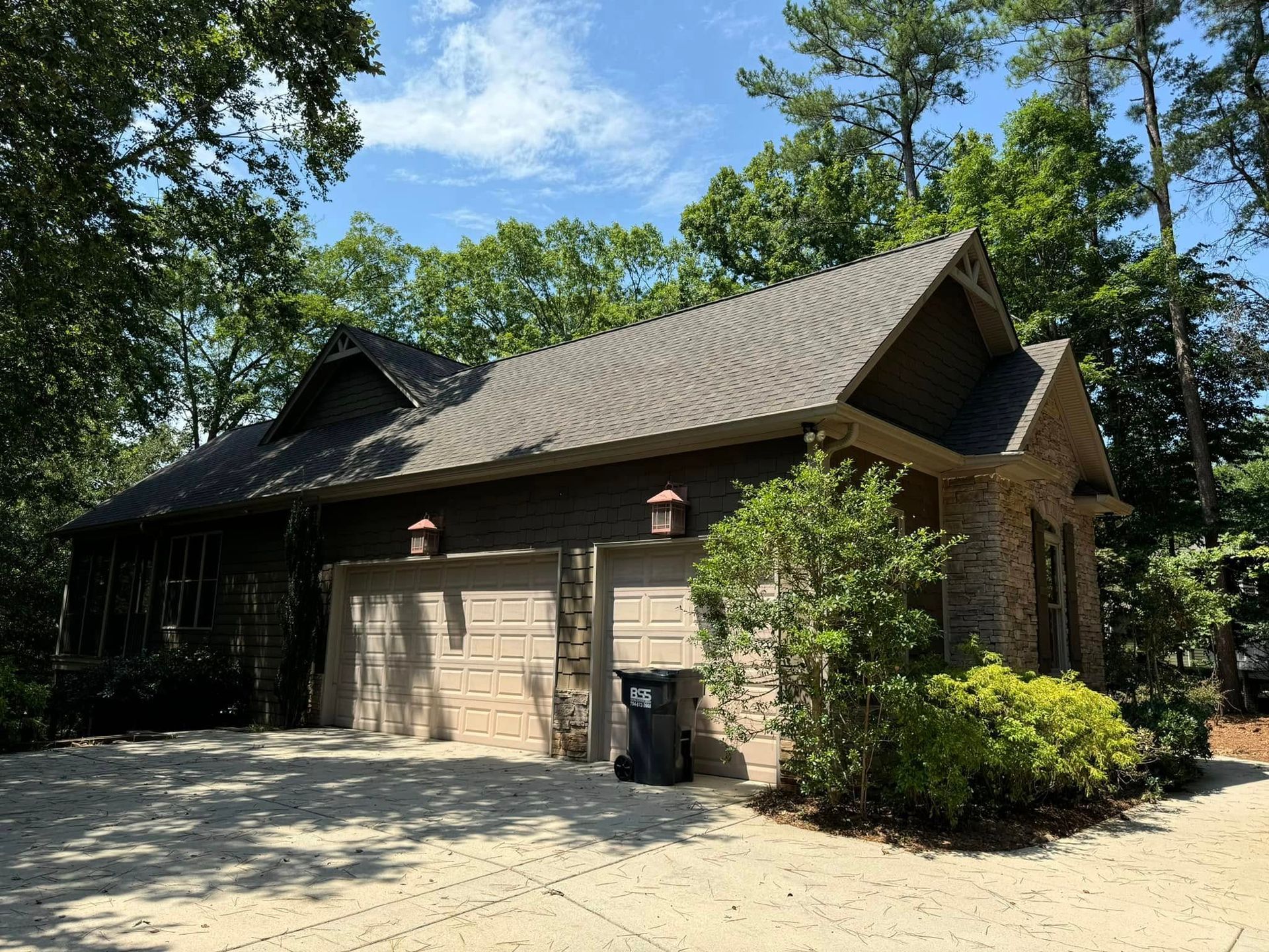 A house with a garage and a trash can in front of it