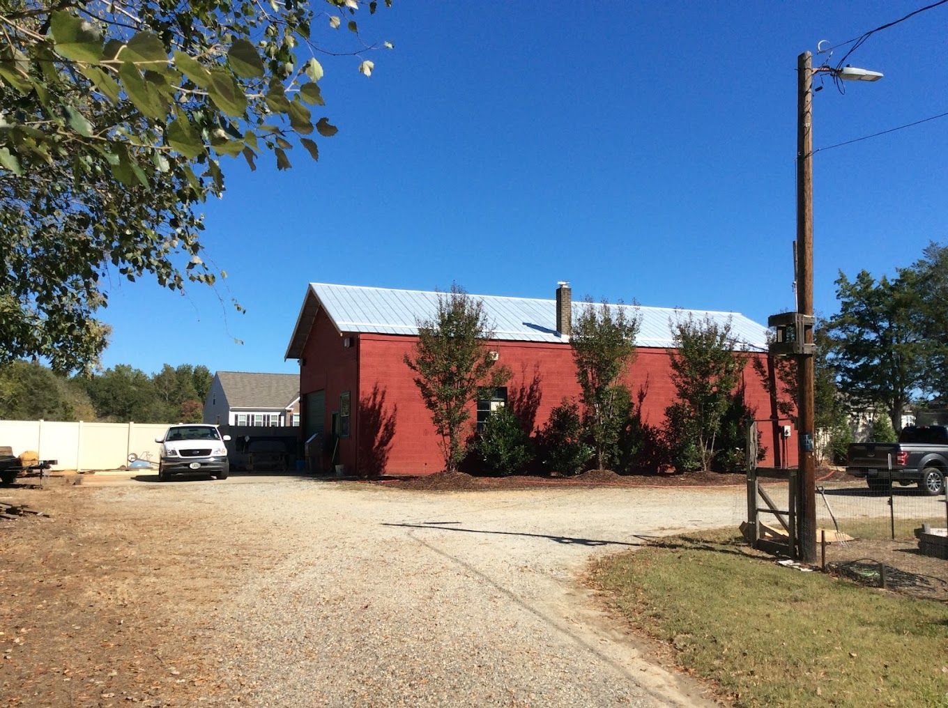 A red barn is sitting in the middle of a dirt road.