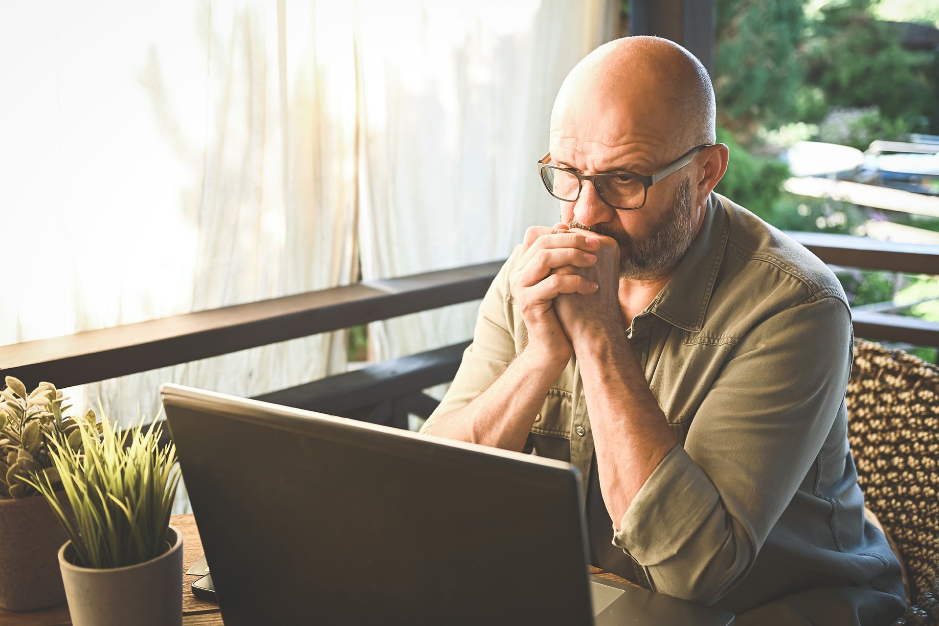A man is sitting at a table using a laptop computer.