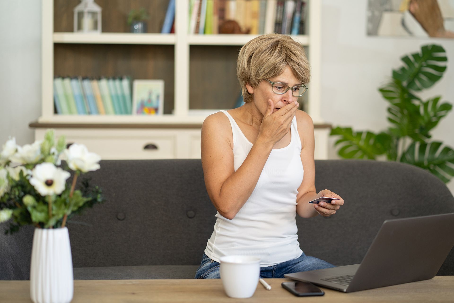 A woman is sitting on a couch using a laptop computer.