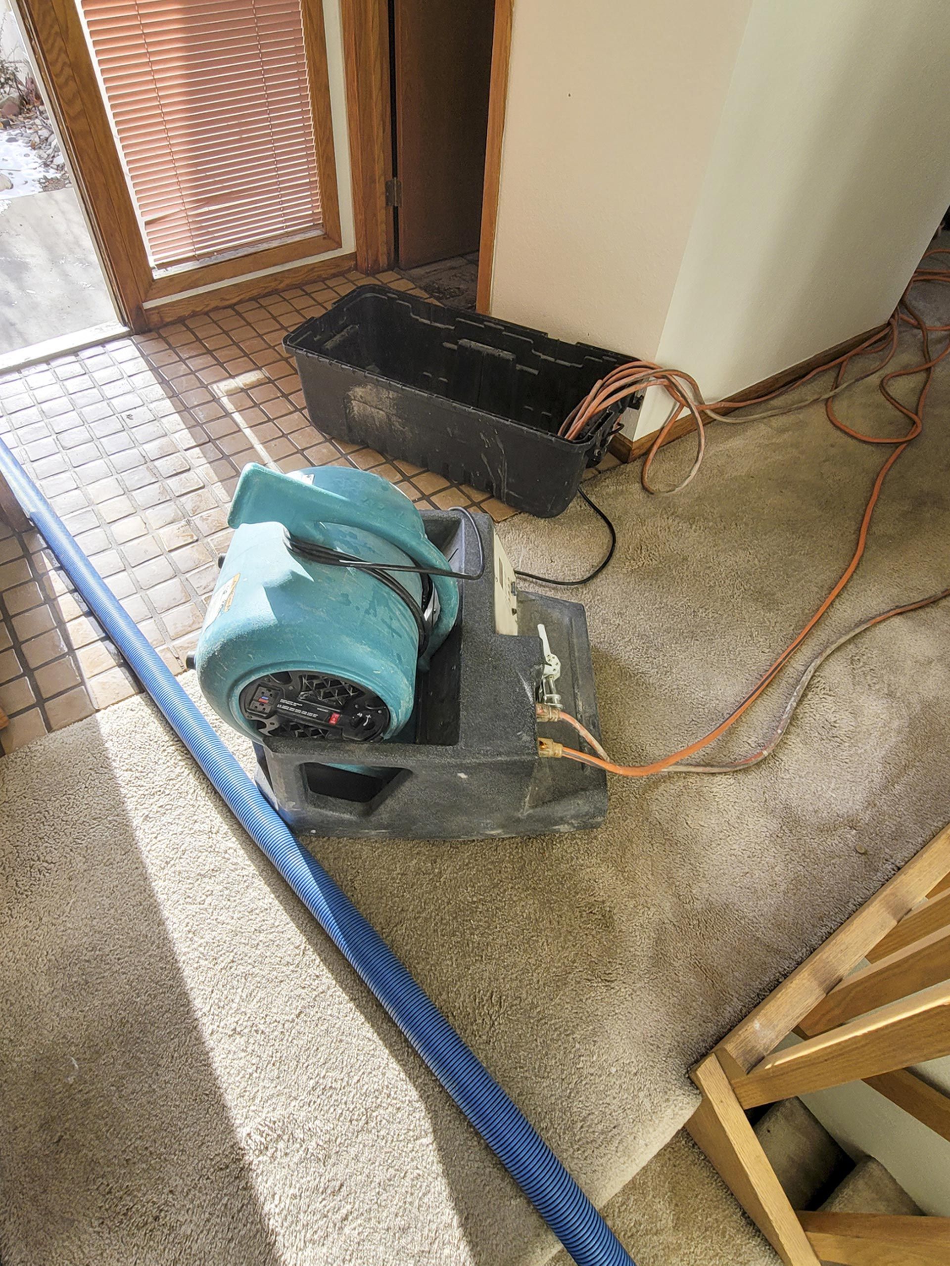 A vacuum cleaner is sitting on the floor next to a hose. A vacuum cleaner is sitting on the floor next to a hose.