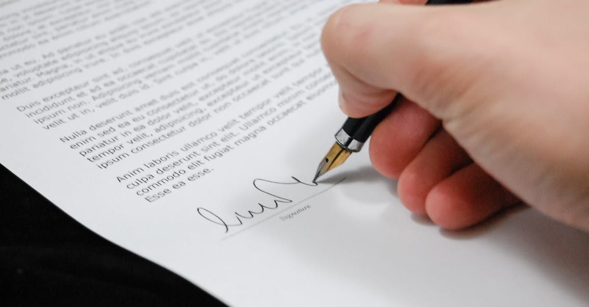 A person is signing a document with a pen.