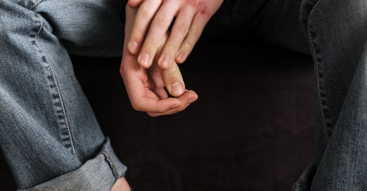 A person is sitting on a couch with their hands on their knees.