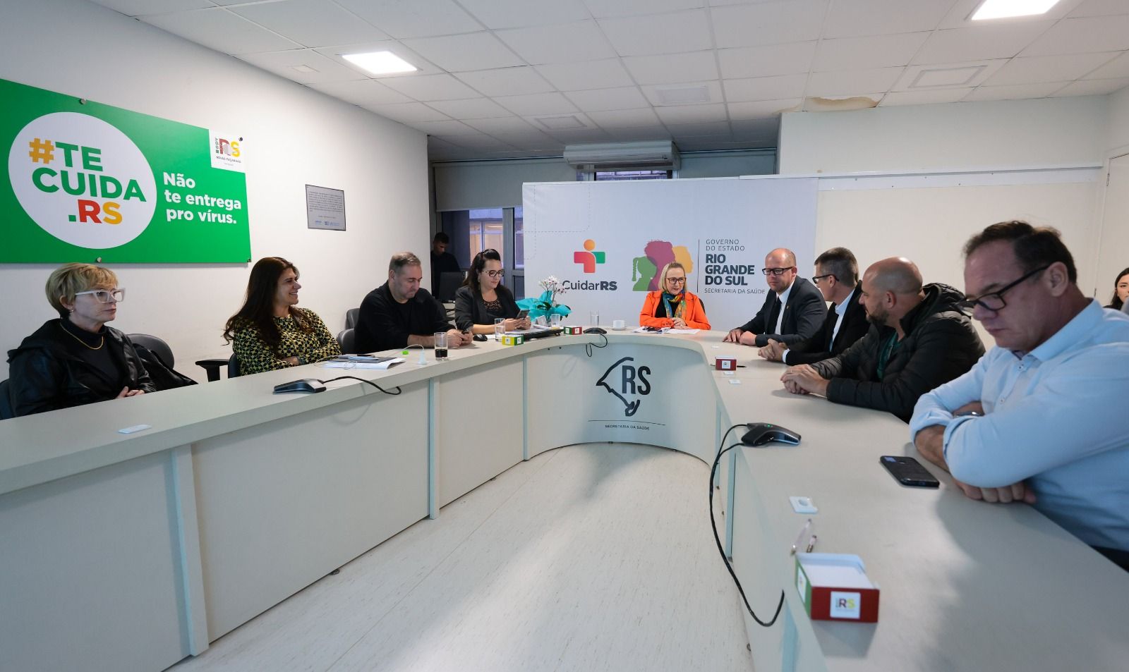 Um grupo de pessoas está sentado em uma longa mesa em uma sala de conferências.