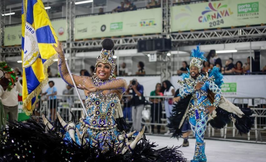 Algumas pessoas em trajes coloridos estão dançando em um desfile.