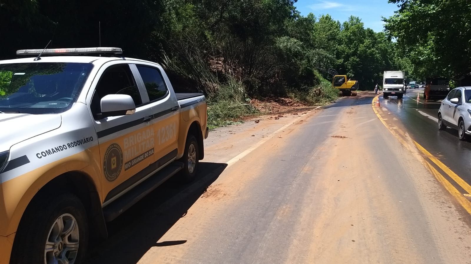 Um caminhão amarelo e branco está estacionado na beira de uma estrada.