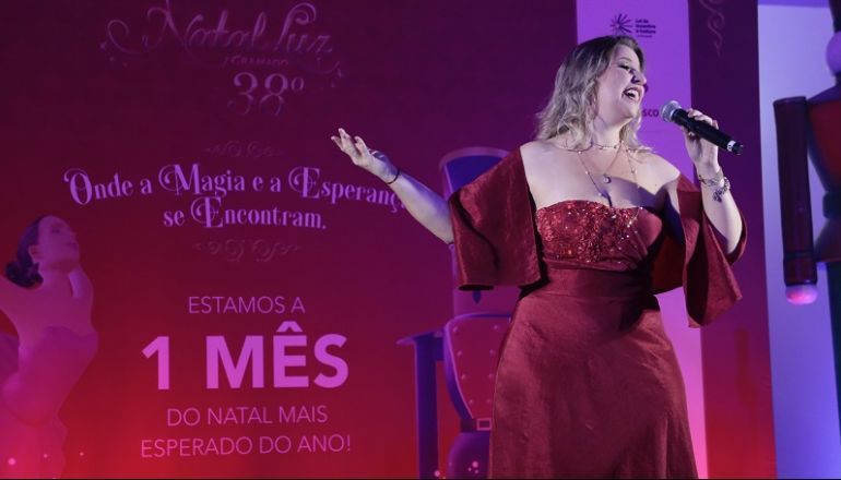 Uma mulher de vestido vermelho está cantando em um microfone.