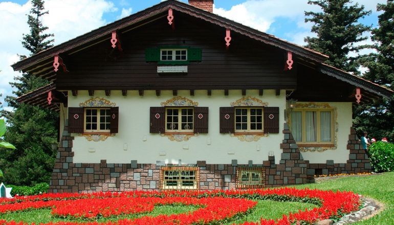 Uma casa com muitas janelas e flores na frente