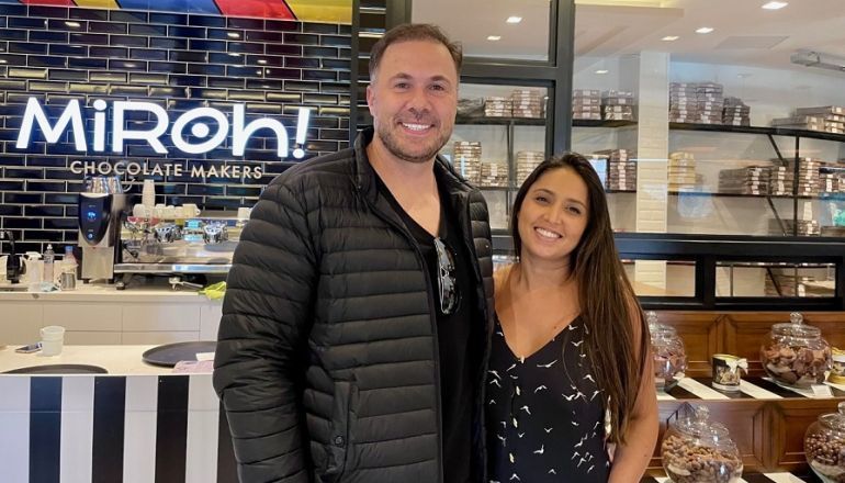 Um homem e uma mulher estão em frente a uma loja de chocolates.