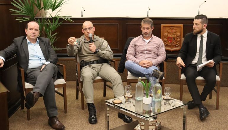 Um grupo de homens está sentado ao redor de uma mesa em uma sala.