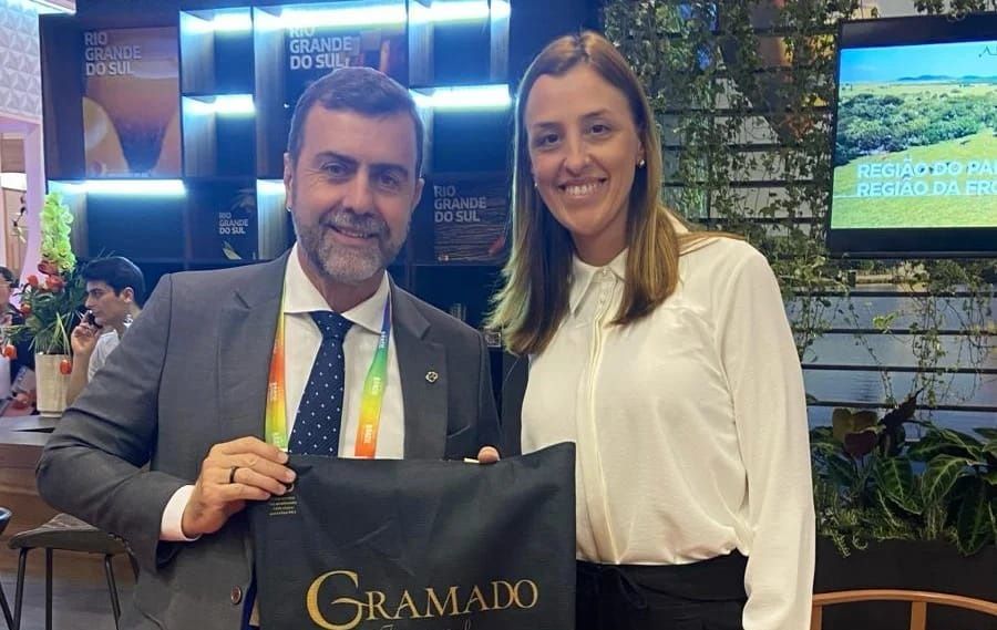 Um homem e uma mulher estão um ao lado do outro segurando uma sacola que diz Gramado.