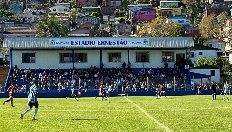 Um campo de futebol com um prédio ao fundo que diz estádio ernestao