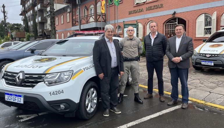 Um grupo de homens posa para uma foto em frente a um carro da polícia.