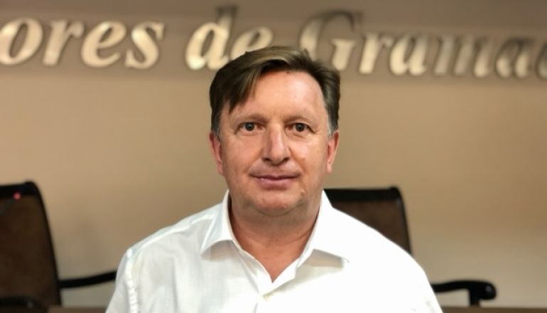 Um homem de camisa branca está sentado em frente a uma placa que diz minérios de granada