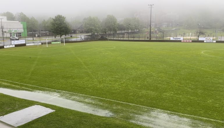 Um campo de futebol com muita água em um dia de neblina.