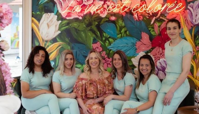 Um grupo de mulheres posa para uma foto em frente a um mural de flores.