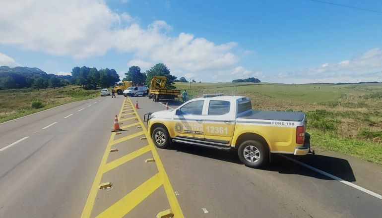 Um caminhão amarelo e branco está estacionado na beira de uma estrada.