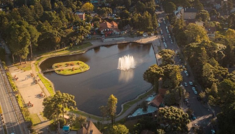 Uma vista aérea de um lago com uma fonte no meio cercada por árvores.