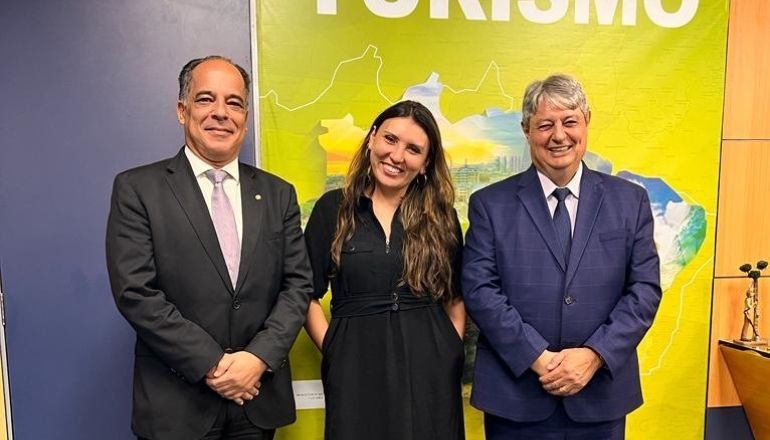 Três pessoas de terno e gravata posam para uma foto.