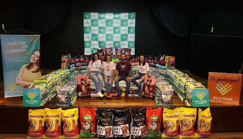 Um grupo de pessoas está em um palco cercado por sacos de comida.