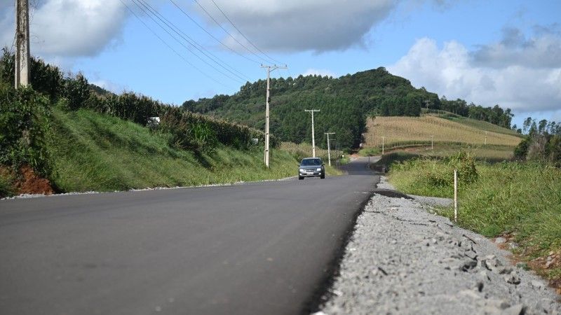 Um carro está dirigindo por uma estrada com uma montanha ao fundo