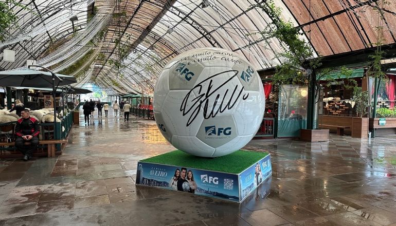 Uma grande bola de futebol está em cima de uma caixa em um shopping.