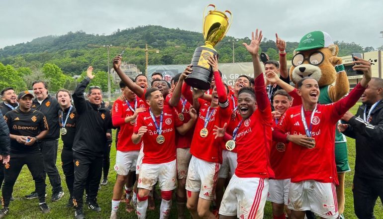 Um grupo de jogadores de futebol segura um troféu em um campo.