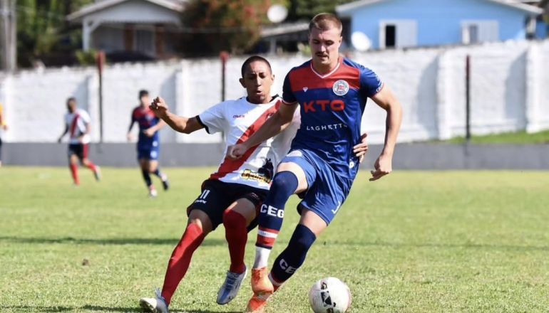 Dois jogadores de futebol estão jogando futebol em um campo.